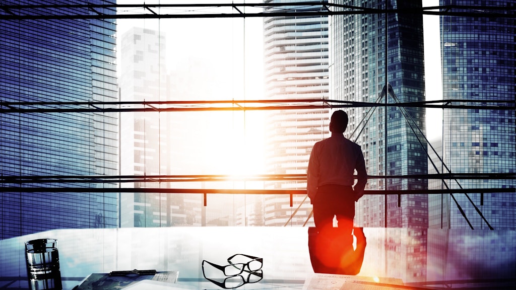 Un homme regarde par la fenêtre d'un grand immeuble.