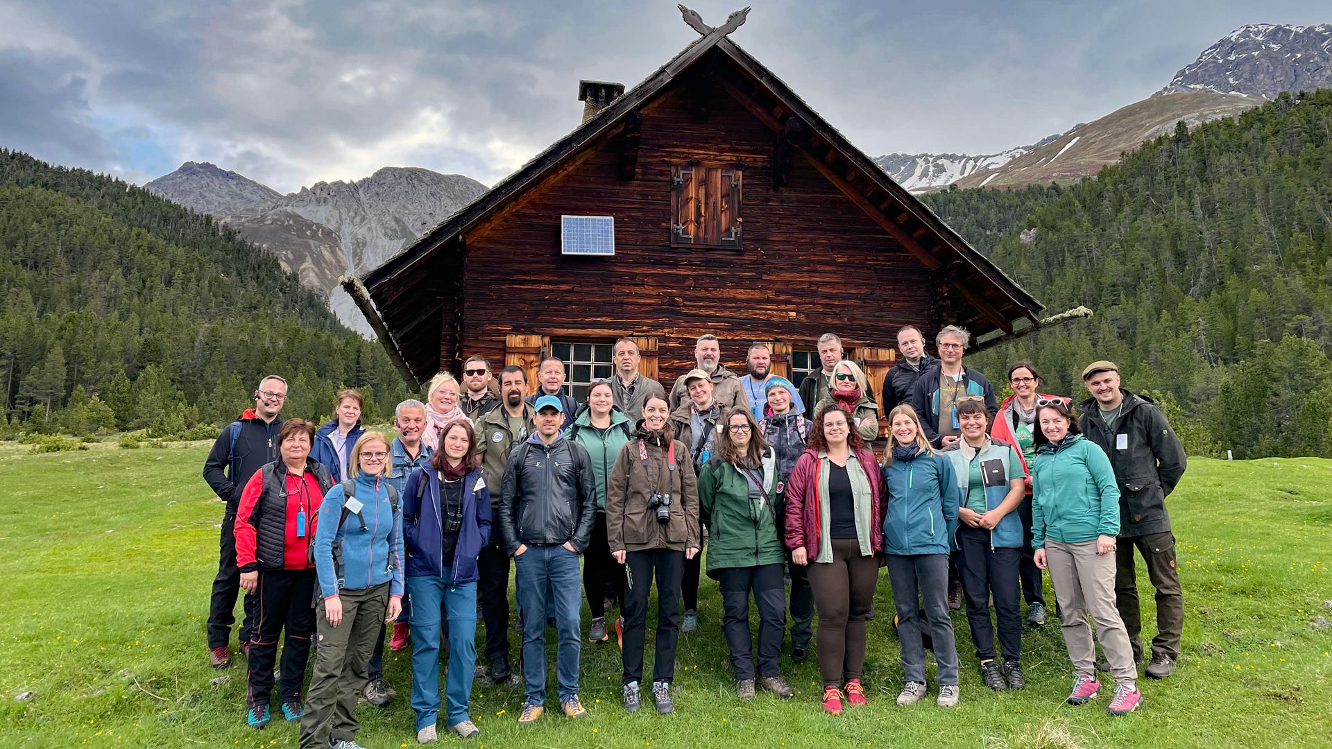 Groupe de personnes devant un chalet dans un pré