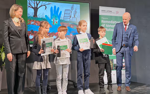 Eine Frau, vier Kinder und ein Mann stehen vor einem Gemälde.