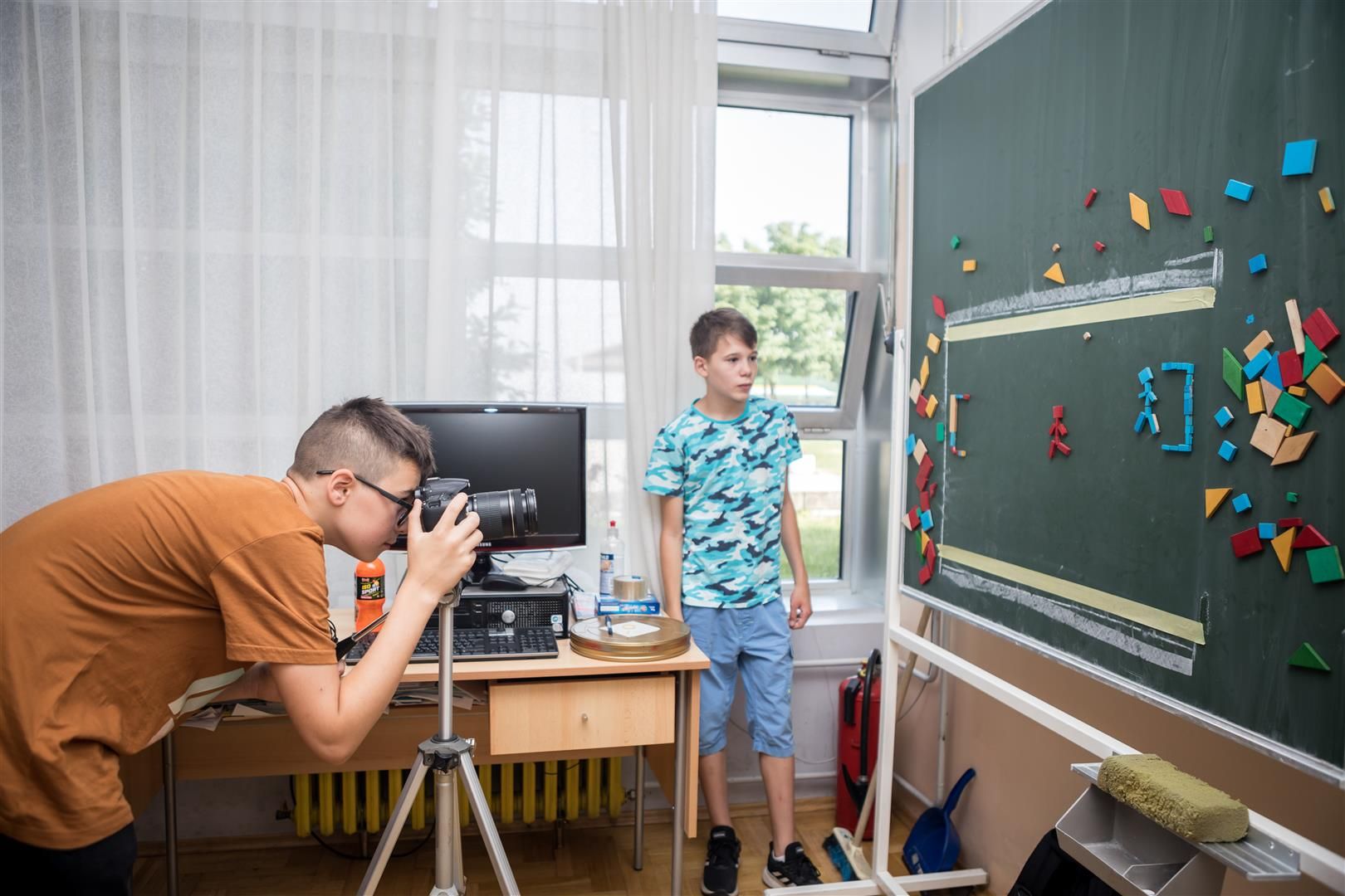 Two boys take a picture from a blackboard.