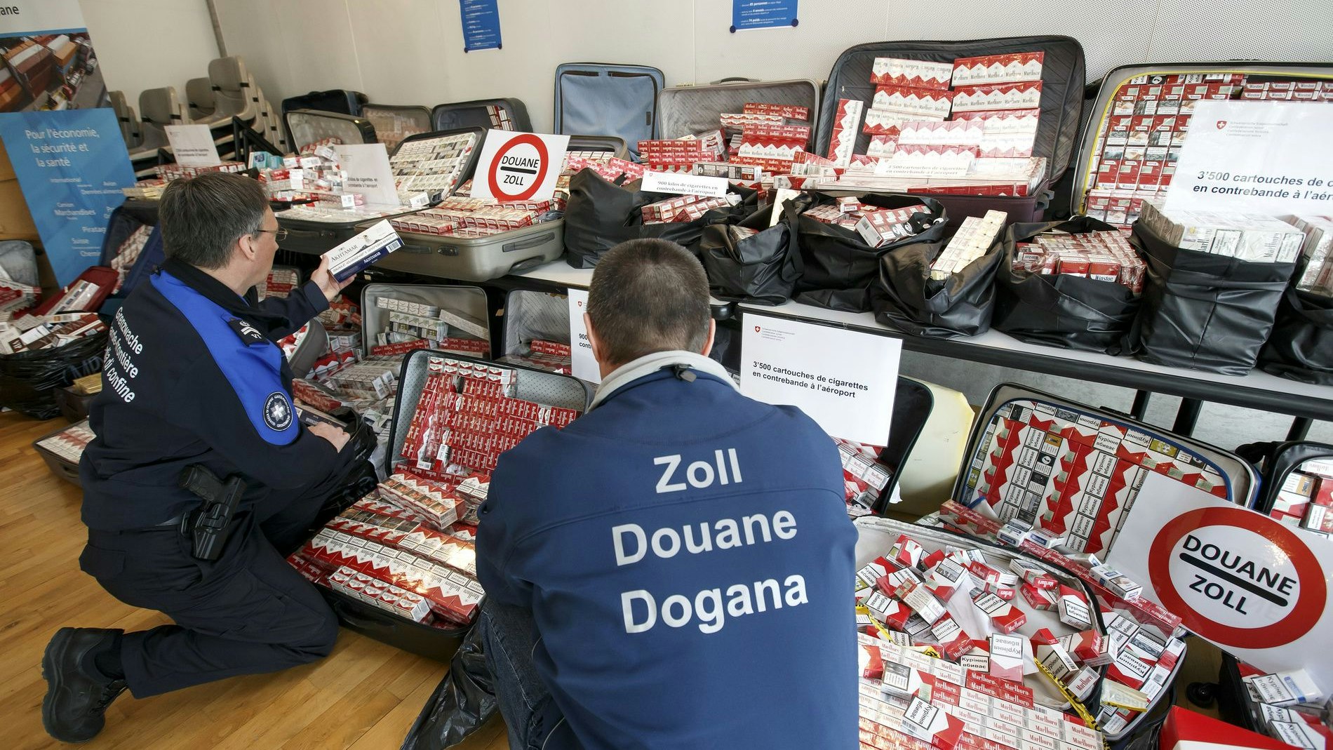 A border guard and a customs officer present 3500 cartons of cigarettes after a customs seizure at Geneva airport.